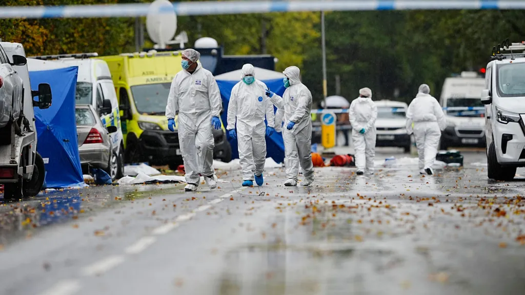 Forensics officers search the streets surrounding the Heaton Park Congregation synagogue. Three officers wear white overalls, blue gloves and face masks.