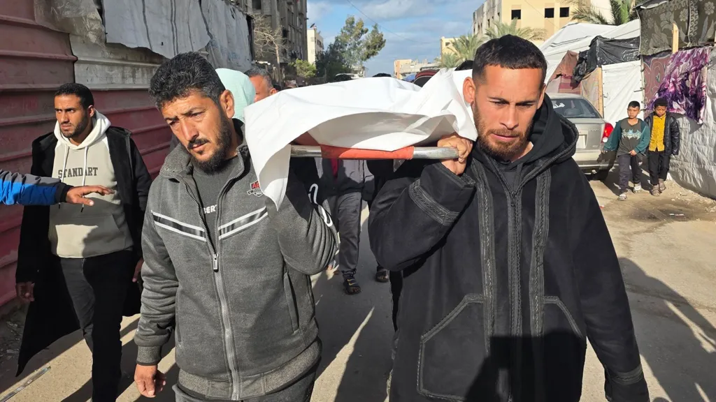 Mourners carry the body of a Palestinian who was reportedly killed in an Israeli air strike, at Nasser hospital, in Khan Younis, southern Gaza (4 February 2026)
