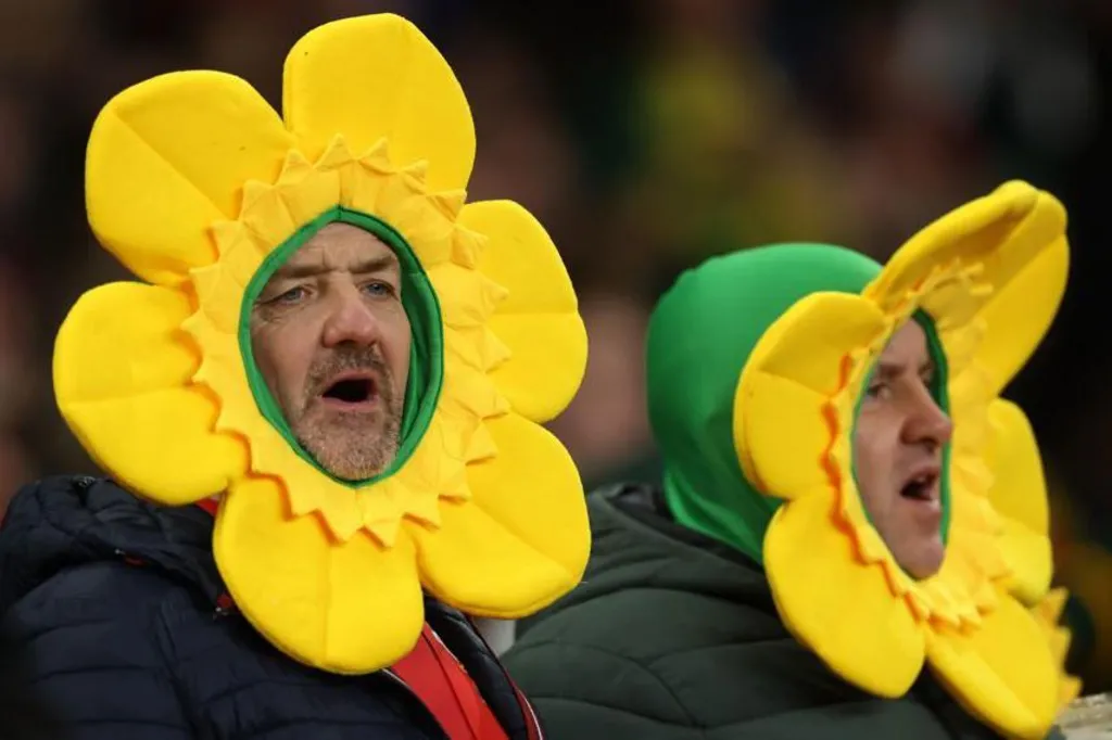 Two men in daffodil hats singing.