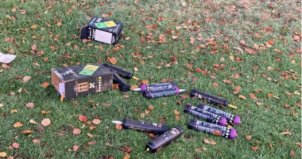 A number of discarded, large nitrous oxide canisters are strewn across the grass.