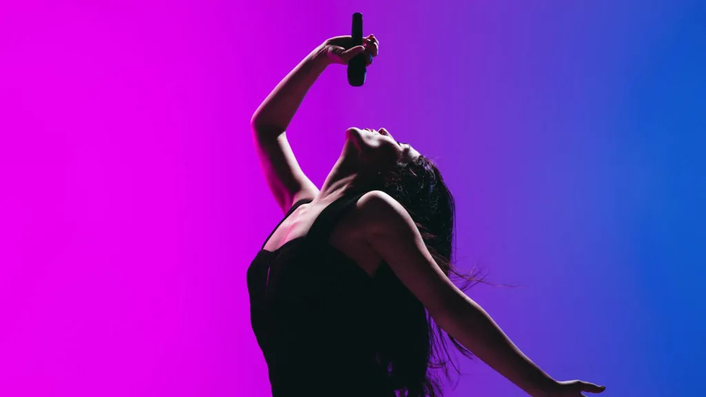 Portrait of young female singer isolated on blue-pink background.