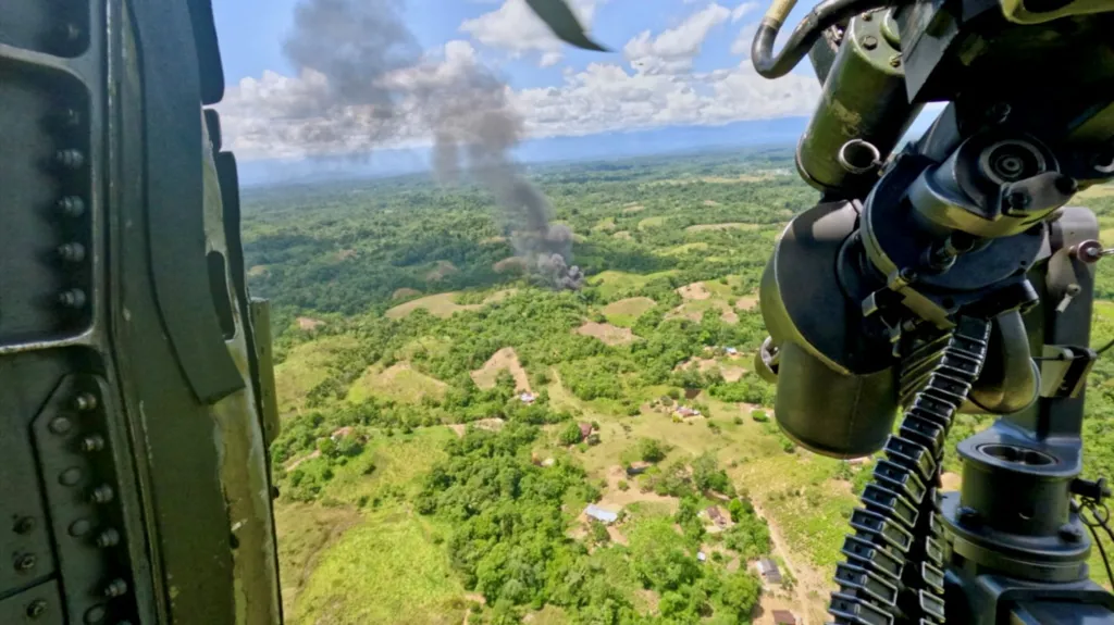 Smoke is seen rising in the distance after the commandos set fire to a cocaine lab. The picture is taken from the open door of a helicopter. 