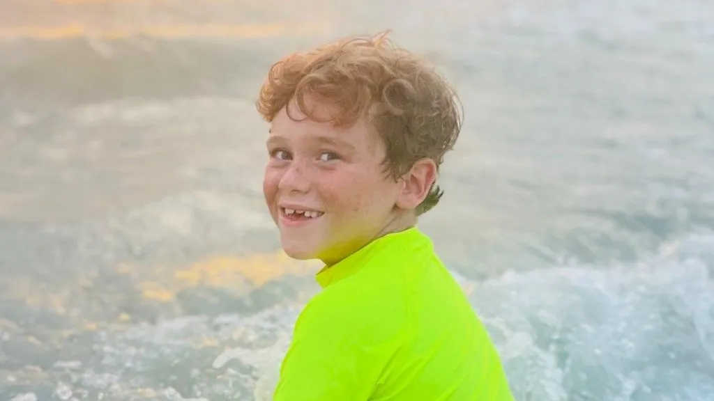 Alfie in a neon green swim top in the sea