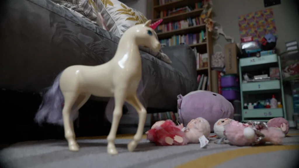 Children's toys, including a unicorn, lie scattered on a child's bedroom floor 