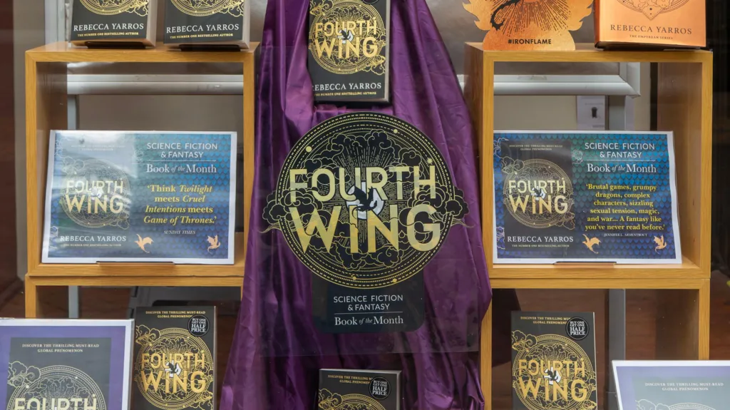 A bookshop window display showing a number of copies and artwork of The Fourth Wing