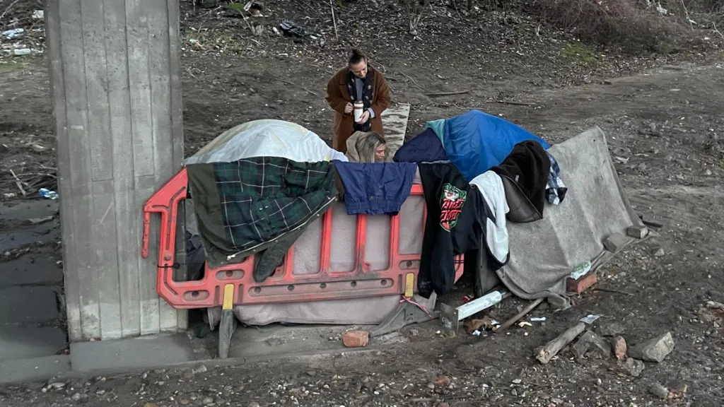 Clothes and jackets are hanging on street furniture next to two tents