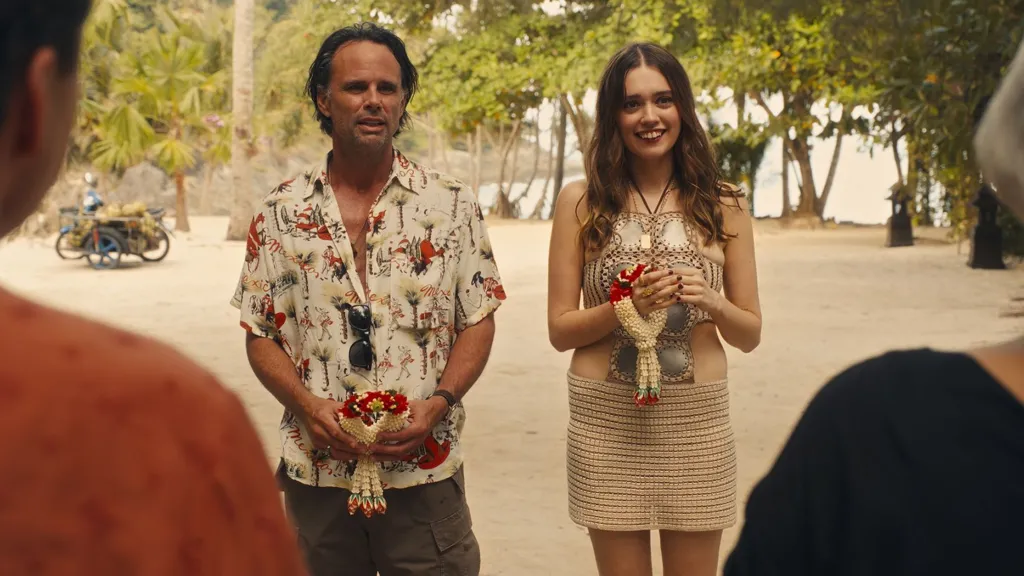 Walton Goggins and Aimee Lou Wood,  in costume, stand next to each other on a beach in a scene from The White Lotus